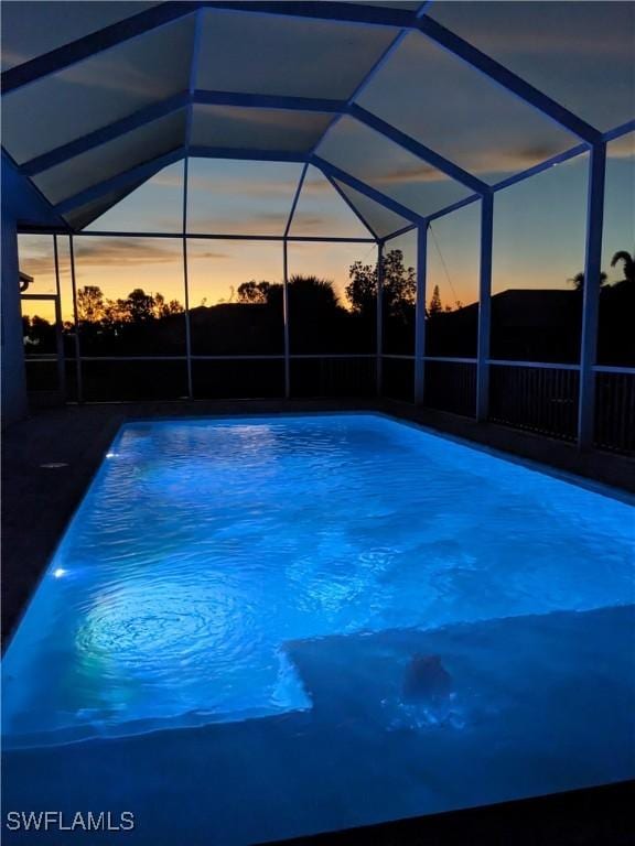 pool at dusk featuring a lanai