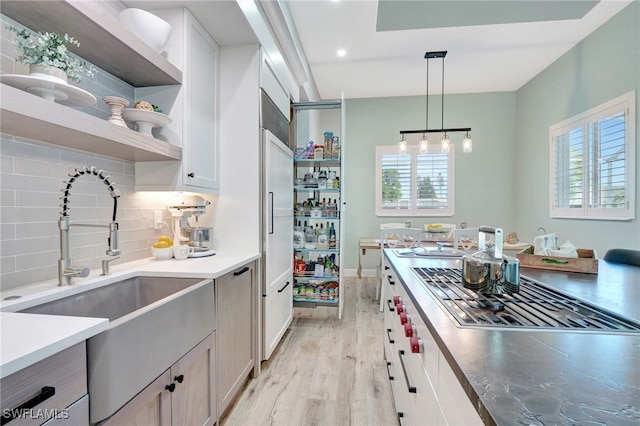 kitchen featuring backsplash, white cabinetry, sink, and pendant lighting