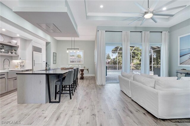 kitchen with a center island, a kitchen breakfast bar, sink, decorative light fixtures, and light hardwood / wood-style floors