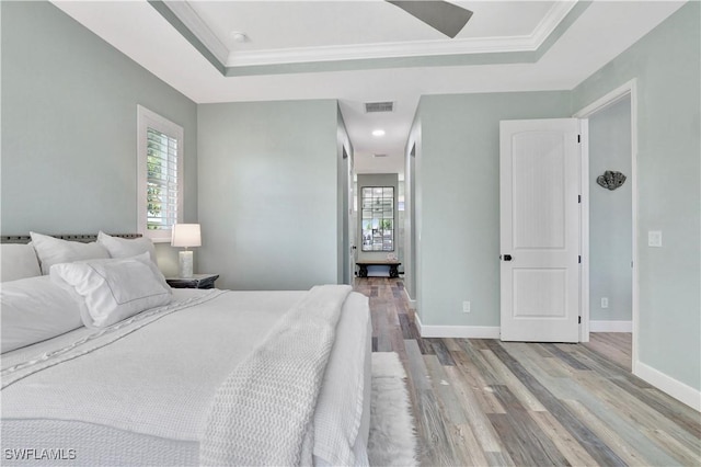 bedroom with a raised ceiling, ceiling fan, crown molding, and light hardwood / wood-style floors