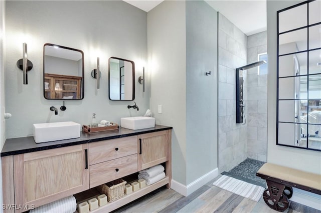 bathroom with a tile shower, hardwood / wood-style floors, and vanity