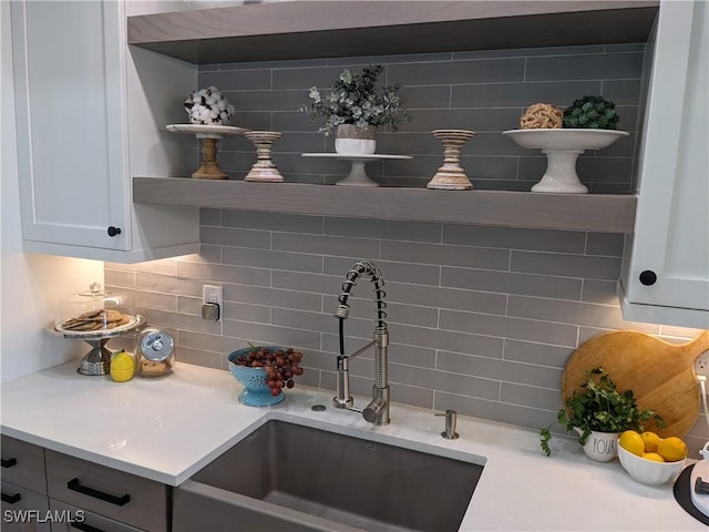 interior space with decorative backsplash, white cabinetry, and sink