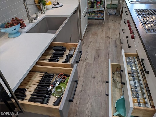 interior space with white cabinets, stainless steel gas stovetop, sink, and light hardwood / wood-style flooring