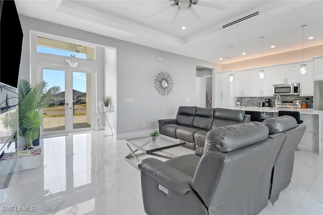 living room featuring a tray ceiling, ceiling fan, and french doors