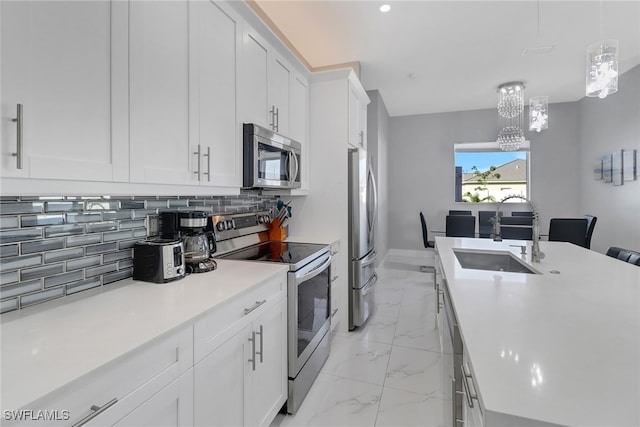 kitchen featuring sink, stainless steel appliances, tasteful backsplash, decorative light fixtures, and white cabinets