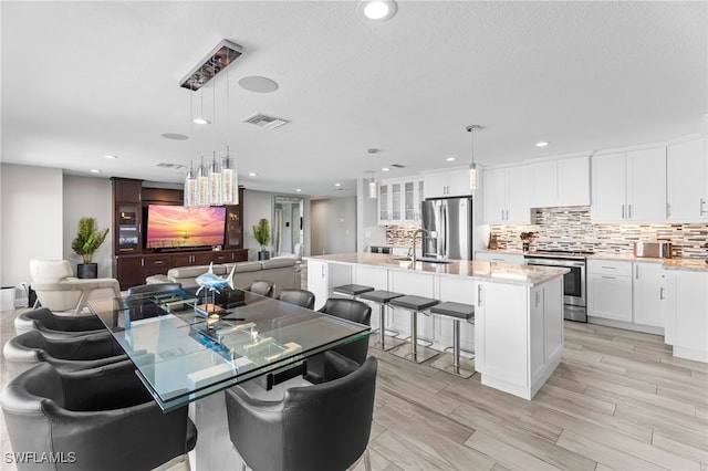 dining area with a textured ceiling, light hardwood / wood-style floors, and sink