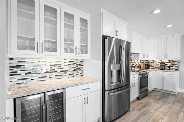 kitchen featuring white cabinets, light stone countertops, stainless steel appliances, and beverage cooler