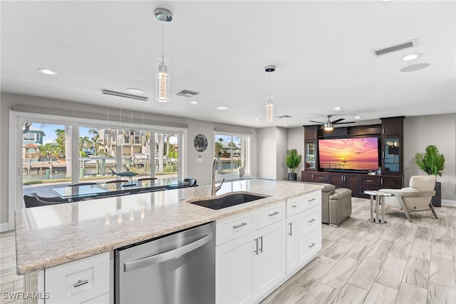 kitchen with visible vents, light stone counters, a kitchen island with sink, dishwasher, and a sink