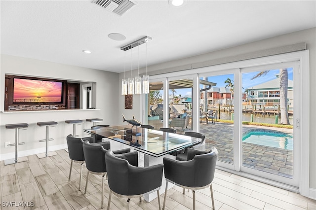 dining area featuring light hardwood / wood-style flooring and a water view