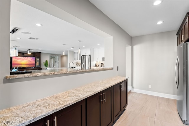 kitchen featuring light stone countertops, stainless steel fridge, dark brown cabinetry, sink, and stainless steel fridge with ice dispenser