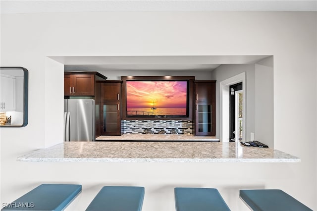 kitchen with stainless steel fridge and light stone countertops