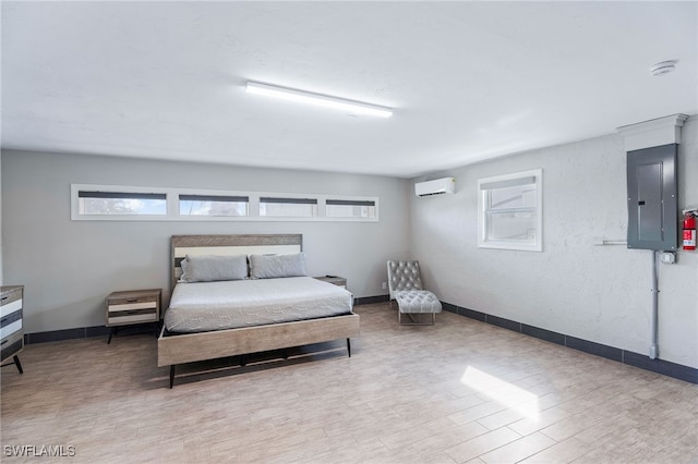 bedroom featuring a wall mounted air conditioner, electric panel, baseboards, and wood finished floors