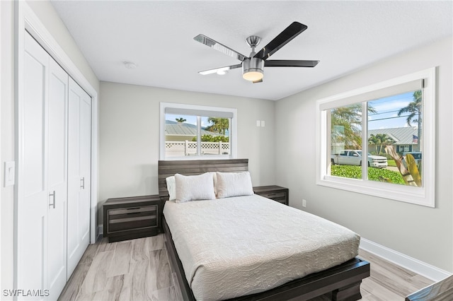 bedroom with ceiling fan, light wood-type flooring, and a closet