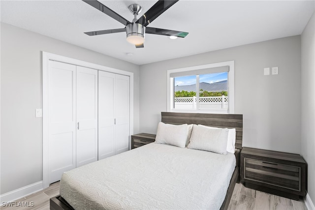 bedroom featuring light wood-style flooring, a closet, baseboards, and a ceiling fan