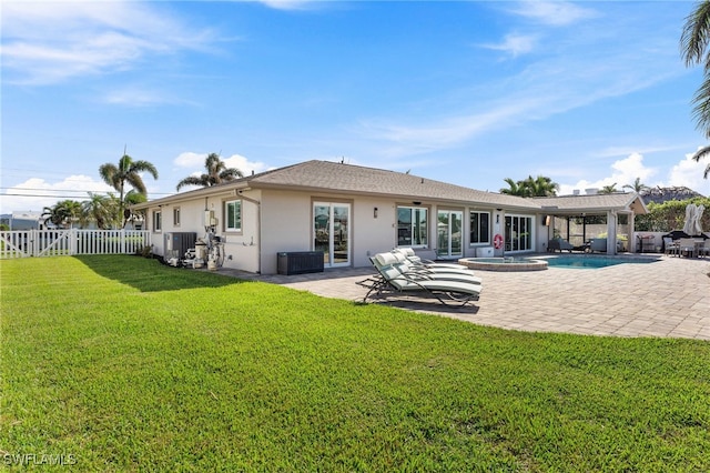 rear view of property featuring central AC, a lawn, a fenced backyard, a patio, and stucco siding