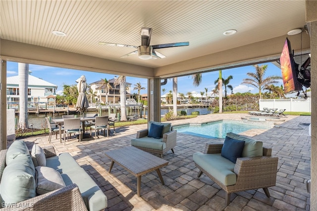 view of patio featuring ceiling fan, a water view, an outdoor hangout area, and a fenced in pool