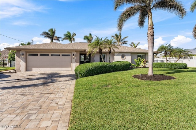 single story home featuring stucco siding, decorative driveway, fence, a front lawn, and a garage
