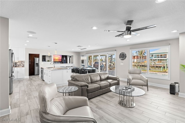 living room featuring ceiling fan, a healthy amount of sunlight, and a textured ceiling