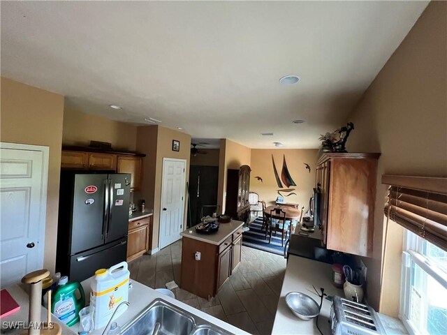 kitchen featuring dark hardwood / wood-style flooring, ceiling fan, sink, a kitchen island, and stainless steel refrigerator