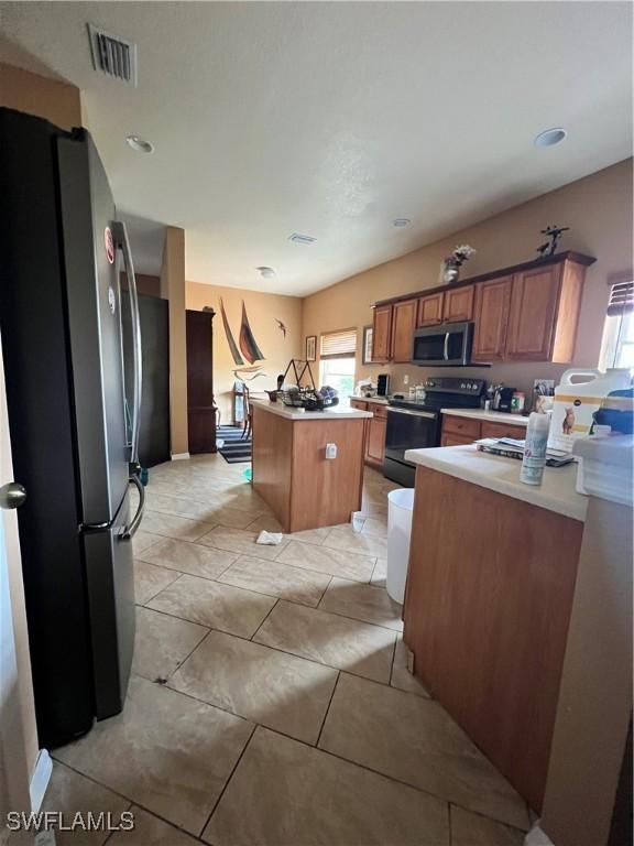 kitchen with a kitchen island, light tile patterned floors, and appliances with stainless steel finishes