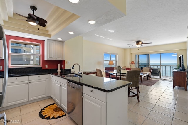 kitchen with sink, stainless steel dishwasher, a textured ceiling, white cabinetry, and kitchen peninsula