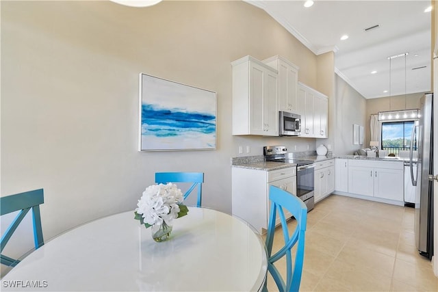 kitchen featuring light stone countertops, white cabinetry, stainless steel appliances, and ornamental molding