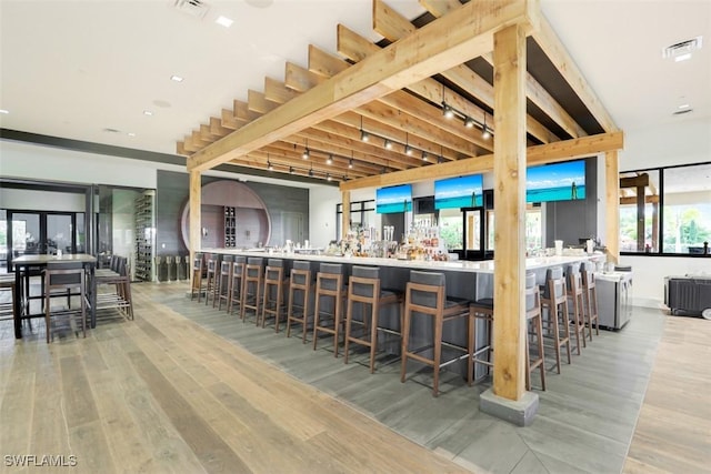 kitchen with a kitchen bar, kitchen peninsula, light hardwood / wood-style flooring, and rail lighting