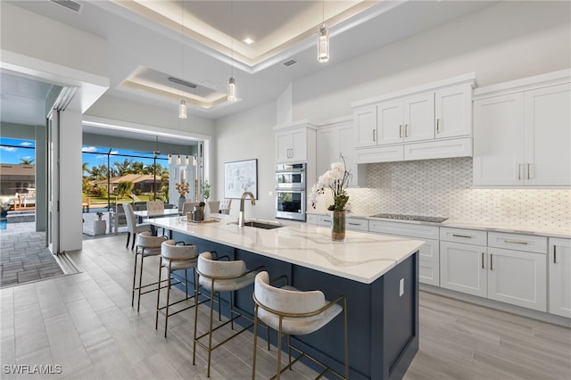 kitchen featuring white cabinetry, a kitchen island with sink, and sink