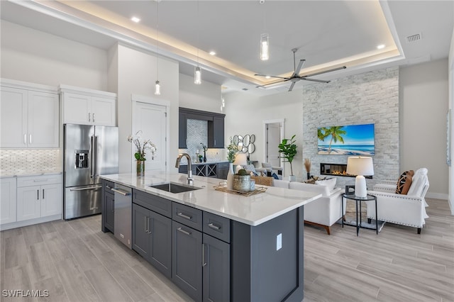 kitchen with sink, decorative light fixtures, a center island with sink, white cabinets, and appliances with stainless steel finishes