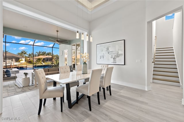 dining space featuring a high ceiling, light hardwood / wood-style flooring, and ceiling fan