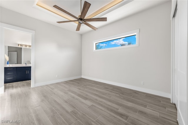 unfurnished bedroom with connected bathroom, ceiling fan, and light wood-type flooring