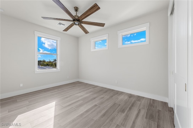 spare room featuring light wood-type flooring, plenty of natural light, and ceiling fan