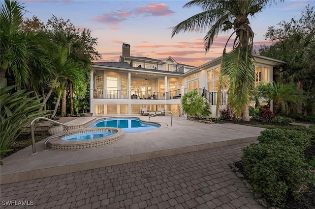 pool at dusk featuring an in ground hot tub, a patio, and ceiling fan