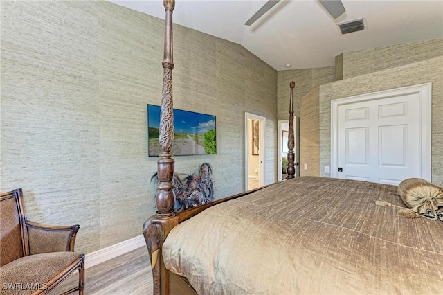 bedroom featuring light hardwood / wood-style flooring, vaulted ceiling, ceiling fan, and ensuite bathroom