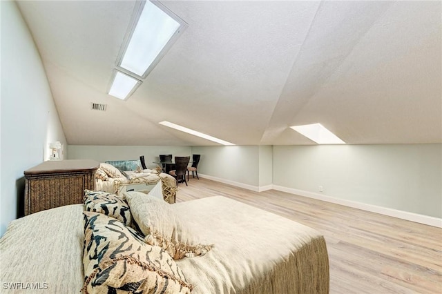 bedroom featuring a textured ceiling, light hardwood / wood-style floors, and vaulted ceiling