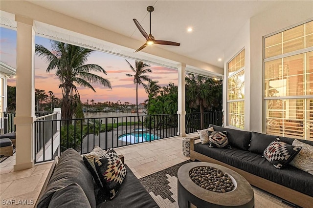 patio terrace at dusk featuring outdoor lounge area, ceiling fan, and a fenced in pool