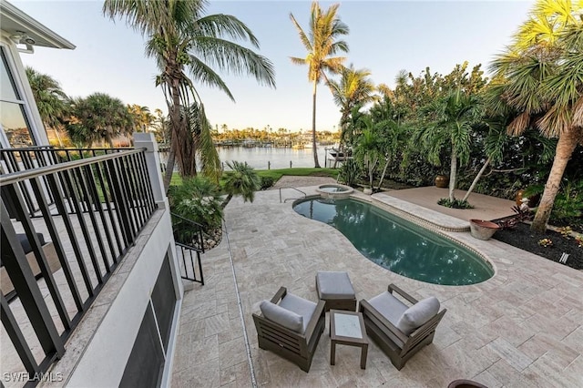 view of pool featuring a patio area, a water view, and an in ground hot tub