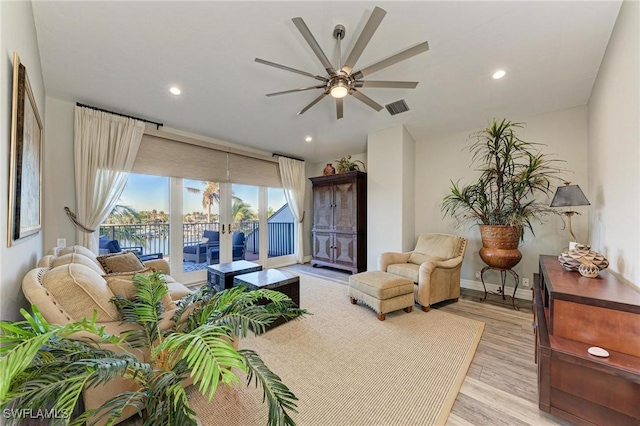 living room with ceiling fan, french doors, a water view, and light wood-type flooring