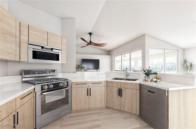 kitchen featuring light brown cabinets, sink, vaulted ceiling, light hardwood / wood-style floors, and stainless steel appliances