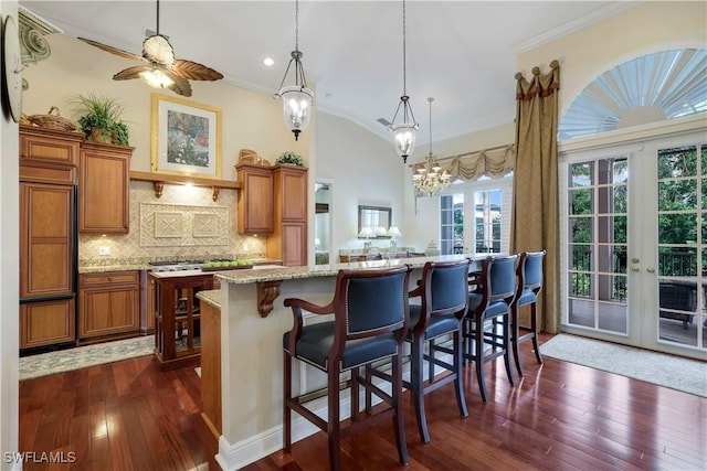 kitchen with pendant lighting, dark hardwood / wood-style floors, ceiling fan, and a breakfast bar area