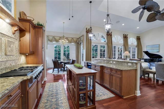 kitchen featuring backsplash, dark wood-type flooring, ceiling fan with notable chandelier, and stainless steel gas cooktop