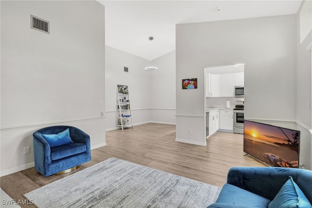 living room with light hardwood / wood-style flooring and high vaulted ceiling