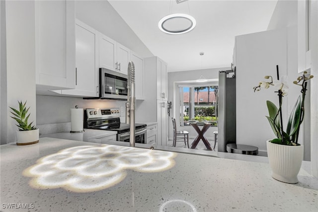 kitchen with white cabinetry, hanging light fixtures, stainless steel appliances, light stone counters, and lofted ceiling