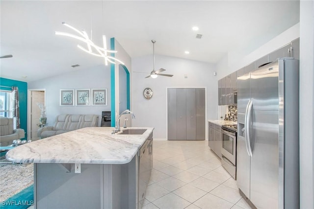 kitchen featuring ceiling fan, sink, lofted ceiling, a center island with sink, and appliances with stainless steel finishes