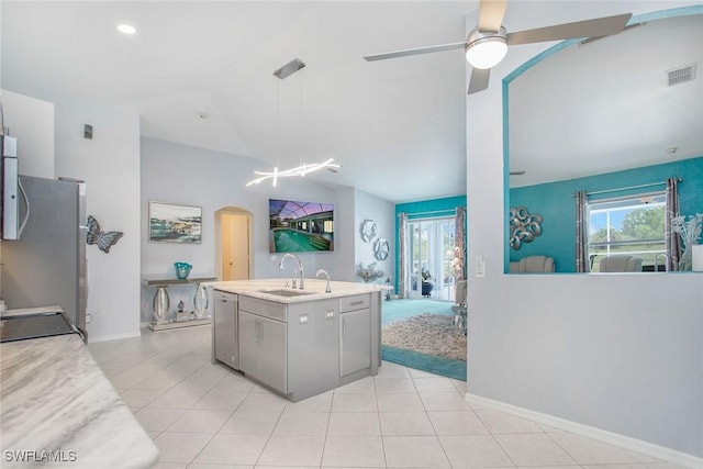 kitchen featuring a center island with sink, sink, hanging light fixtures, ceiling fan, and appliances with stainless steel finishes