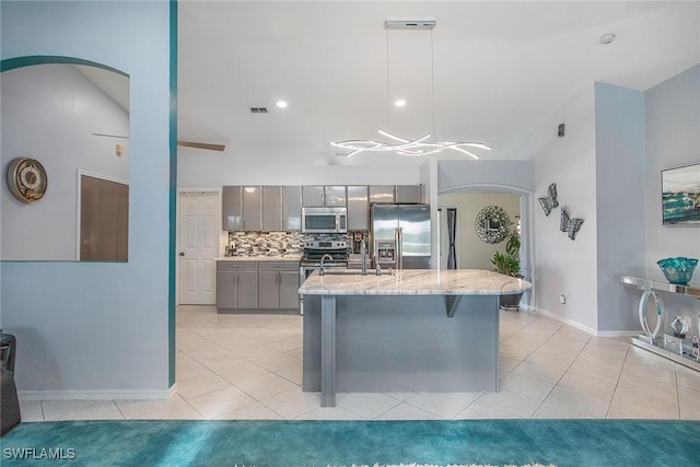 kitchen featuring hanging light fixtures, backsplash, gray cabinets, light tile patterned floors, and appliances with stainless steel finishes