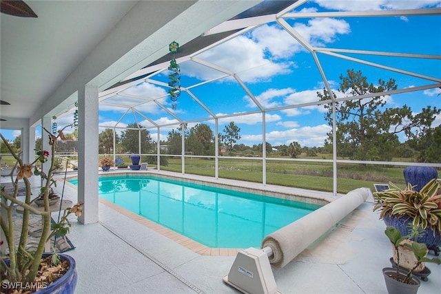 view of swimming pool featuring a yard, a patio, and a lanai