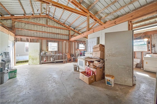 miscellaneous room featuring concrete flooring, beam ceiling, washer / clothes dryer, and high vaulted ceiling