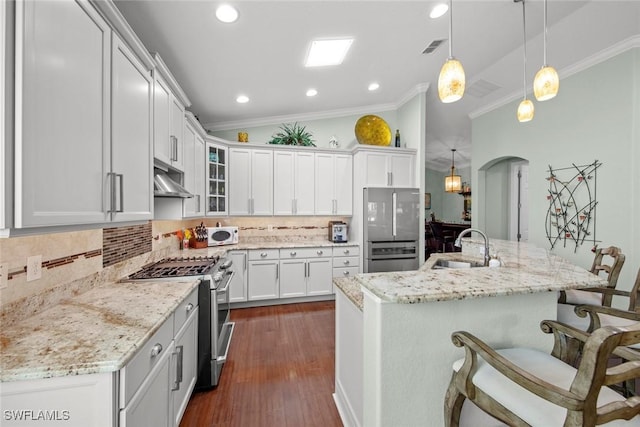 kitchen with backsplash, a center island with sink, sink, decorative light fixtures, and stainless steel appliances