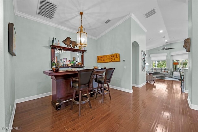 bar featuring ornamental molding, vaulted ceiling, ceiling fan, decorative light fixtures, and dark hardwood / wood-style floors